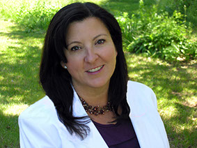 Picture of Allyson Lee in white jacket with lush garden background